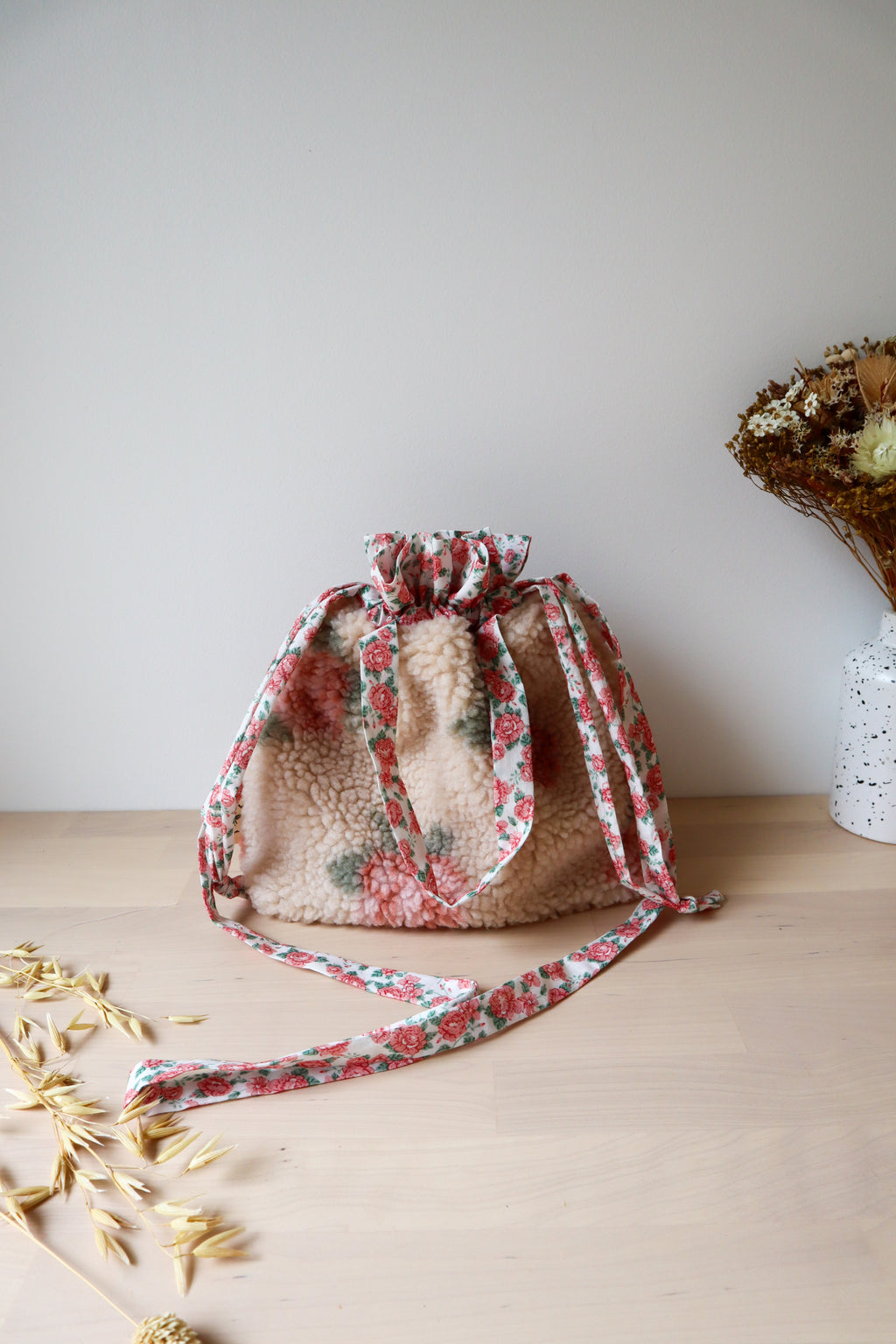 Sac bourse en fausse fourrure beige à fleurs roses, avec sa longue bandoulière fleurie déployée