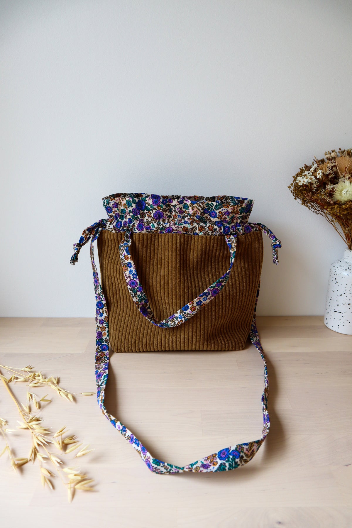 Petit sac bourse ouvert en velours côtelé marron, avec anses et bandoulière à fleurs bleues et violettes